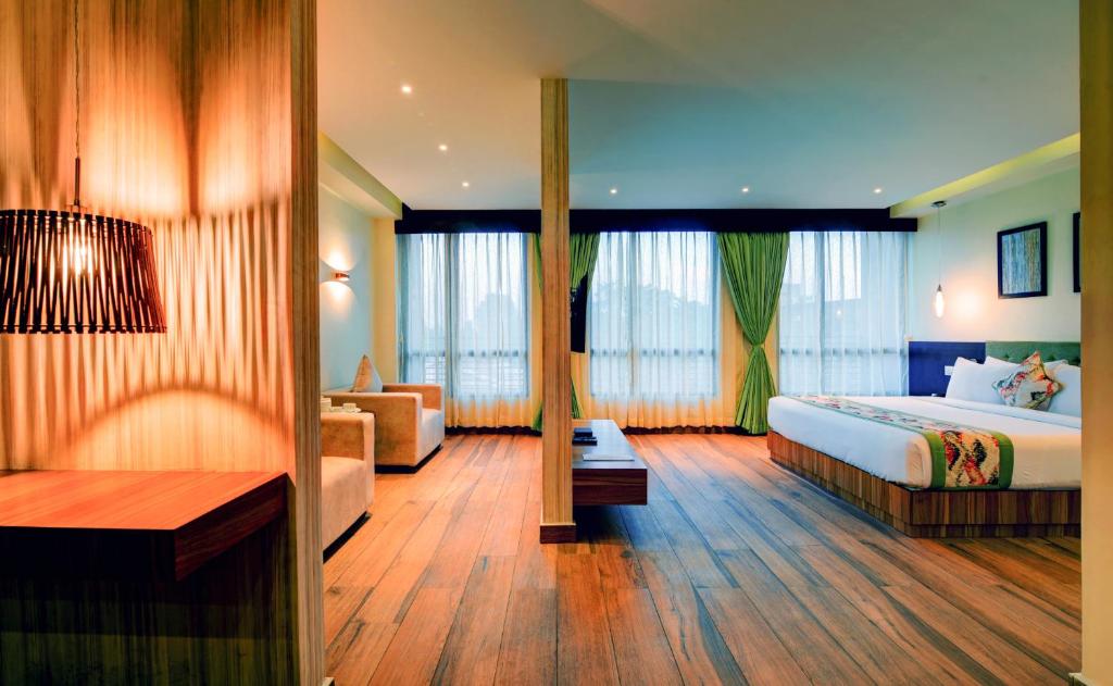 um quarto de hotel com uma cama e um sofá em Udaan Clover Hotel Banquet & Spa em Siliguri