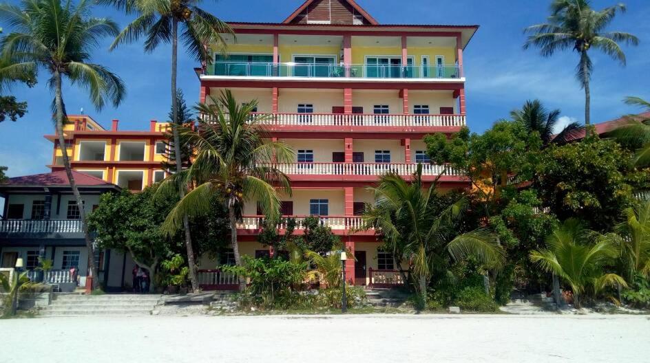 a building on the beach with palm trees in front of it at Melati Tanjong Beach Resort in Pantai Cenang
