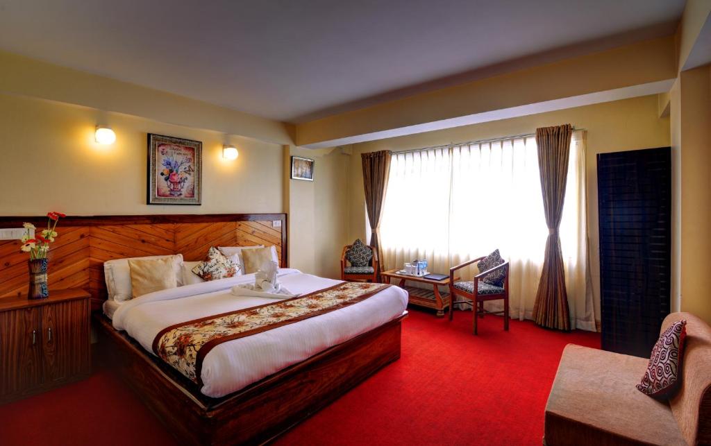 een hotelkamer met een groot bed en een raam bij Hotel White Yak in Darjeeling
