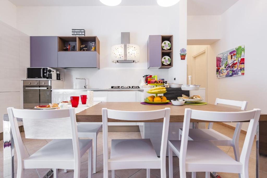 a kitchen with a wooden table and white chairs at B&B Zanzibar - Ospitalità Siciliana in Avola