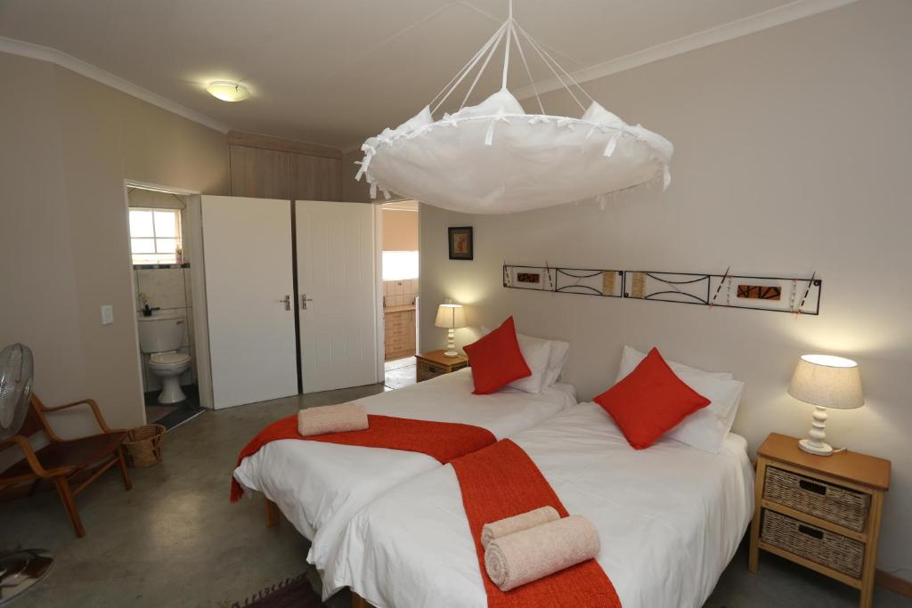 1 dormitorio con 1 cama blanca grande con almohadas rojas en Orange House Self Catering, en Aus