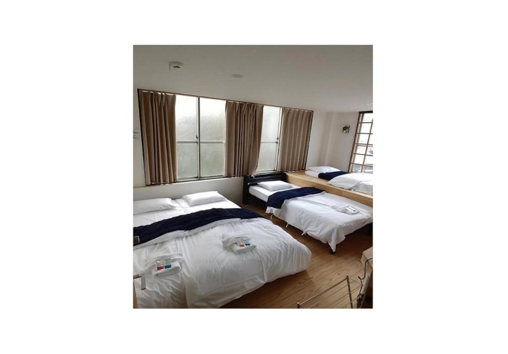 a bedroom with two beds and a window at Nagoya Hostel The Three Smiles / Vacation STAY 13462 in Nagoya