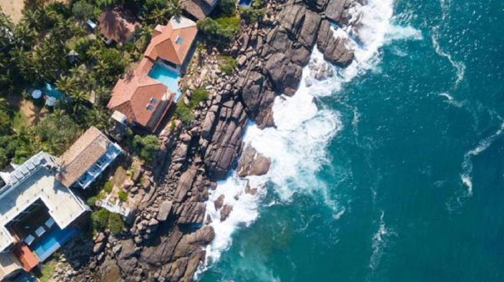 an aerial view of a house on a cliff next to the ocean at Land's End Villa in Unawatuna