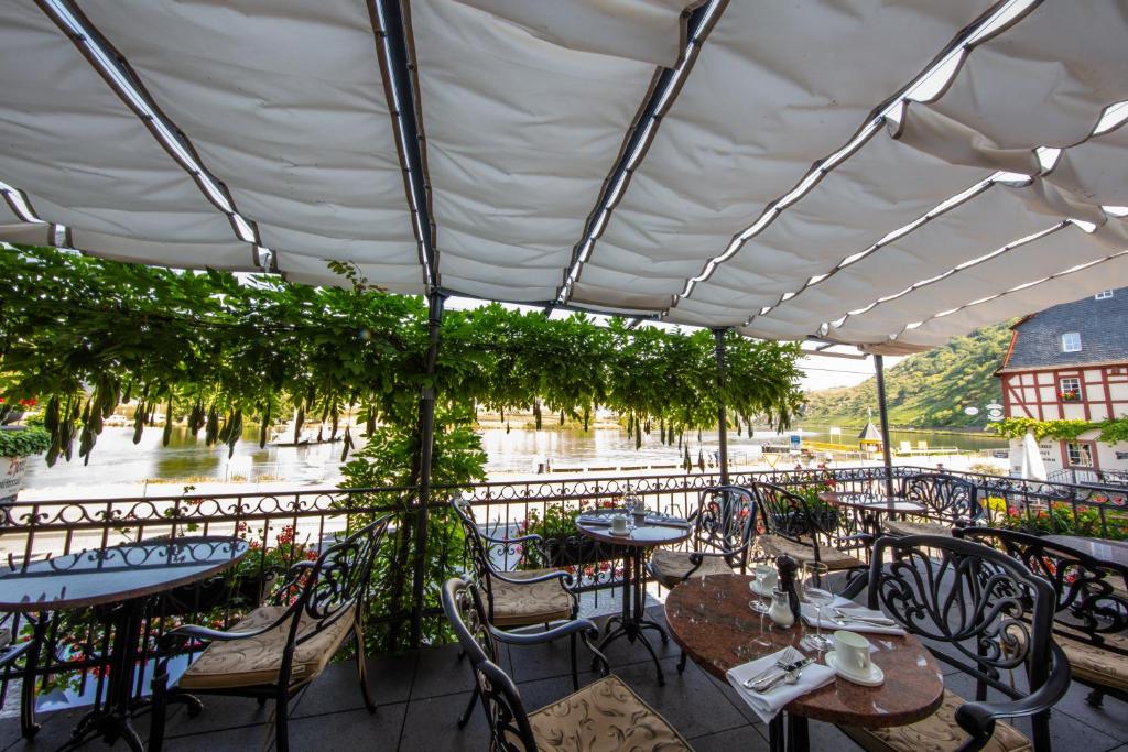 a patio with tables and chairs and a view of a river at Villa Beilstein in Beilstein