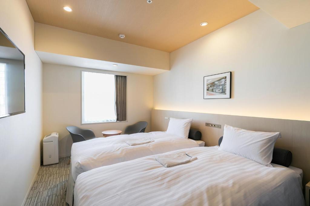 a hotel room with two beds and two lamps at Ginza Capital Hotel Moegi in Tokyo