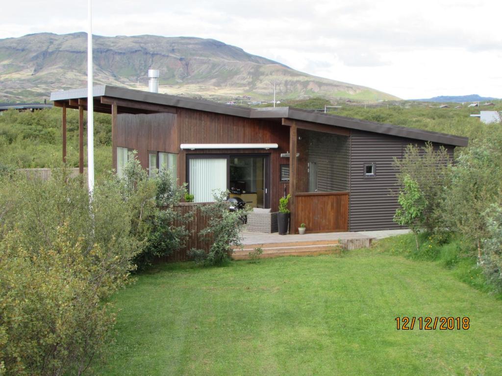 a house on a hill with mountains in the background at Luxury Vacation House for Summer and Winter in Úlfljótsvatn