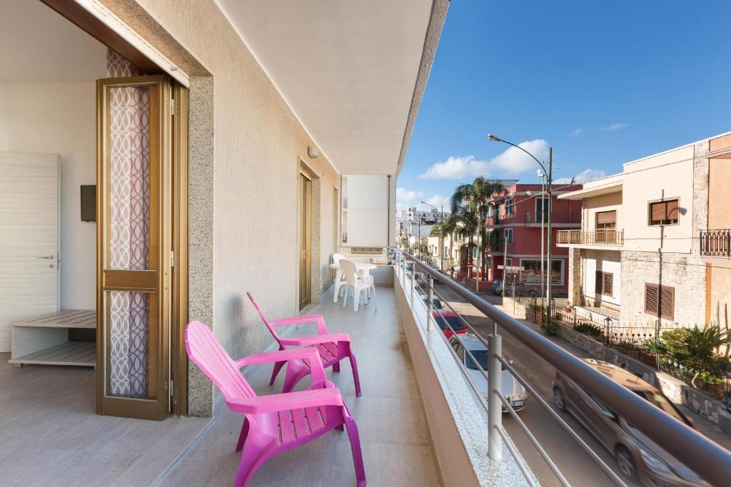 due sedie rosa sedute sul balcone di un edificio di Versomare by BarbarHouse a Porto Cesareo