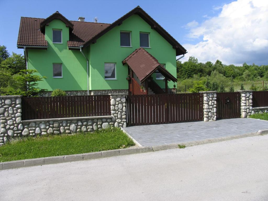 a house with a fence and a stone wall at Penzión v Tatrách in Stará Lesná