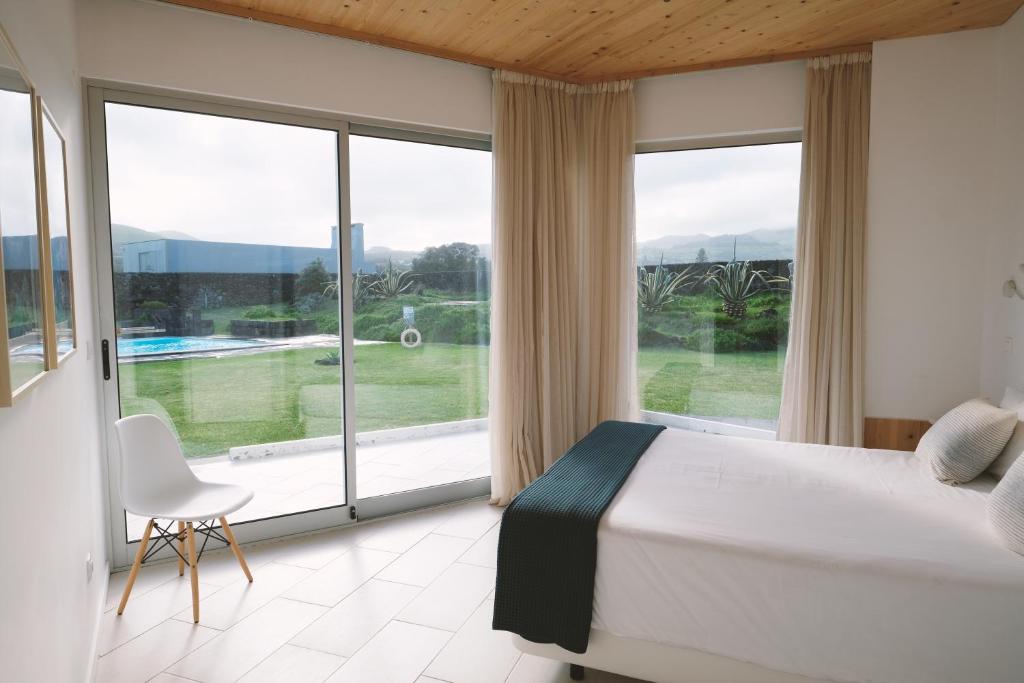 a bedroom with a bed and a large window at Sao Vicente Lodge - Atlantic Retreat in São Vicente Ferreira