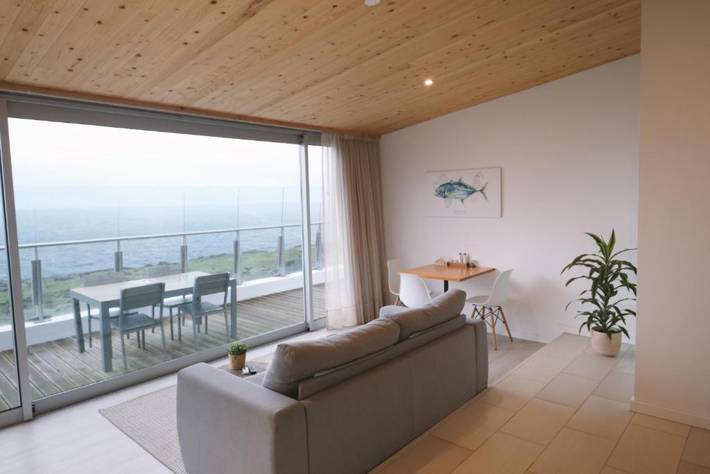 a living room with a couch and a table with a view at Sao Vicente Lodge - Atlantic Retreat in São Vicente Ferreira