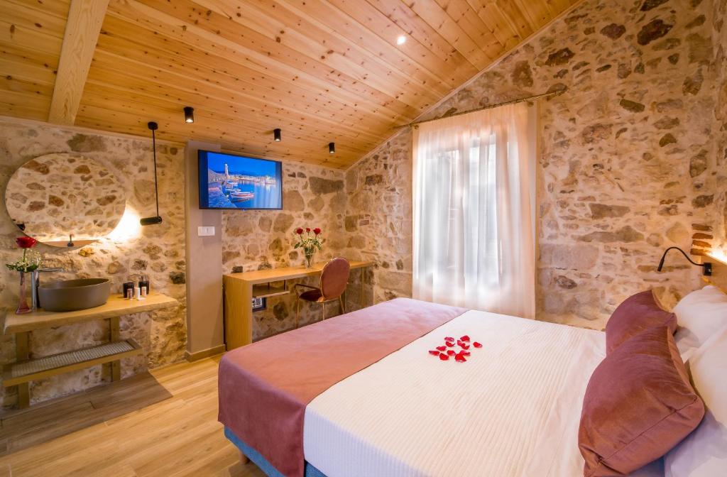 1 dormitorio con 1 cama en una pared de piedra en Elma Suites en Rethymno