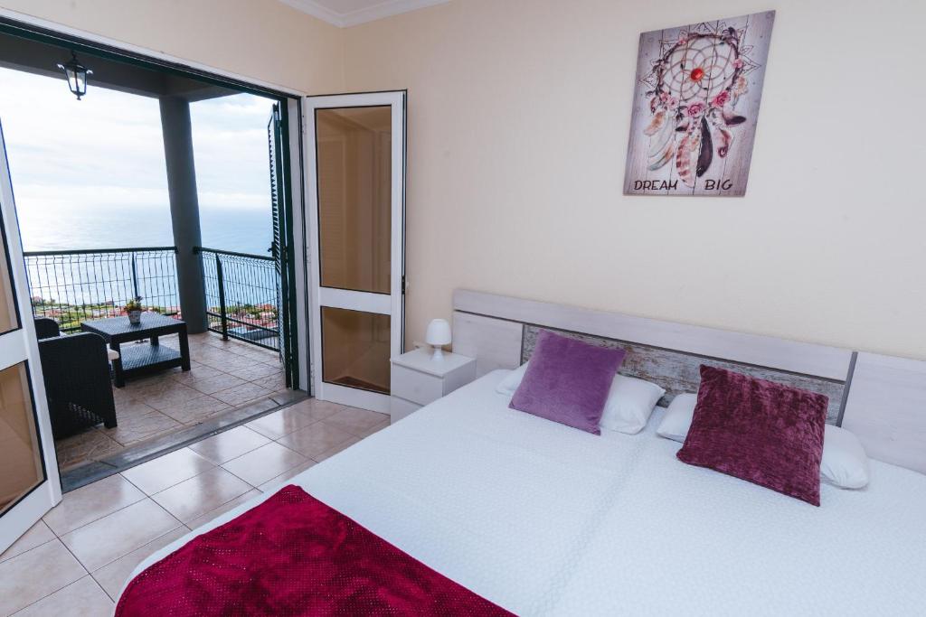 una camera da letto con balcone e letto con cuscini viola di Calheta Holiday Houses ad Arco da Calheta