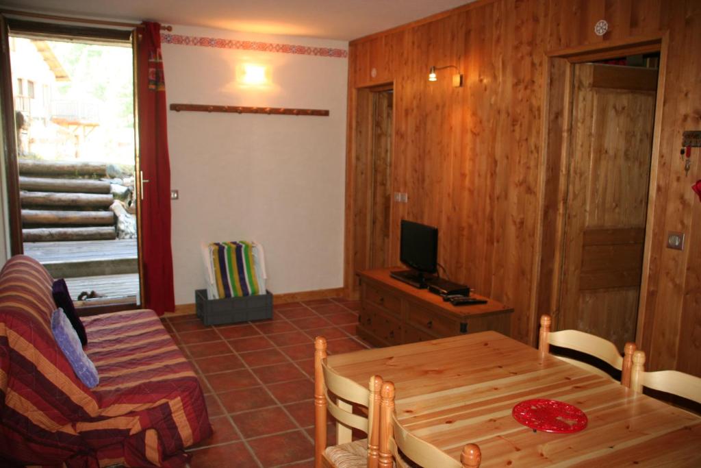 a living room with a table and a television at Le Serre in Abriès