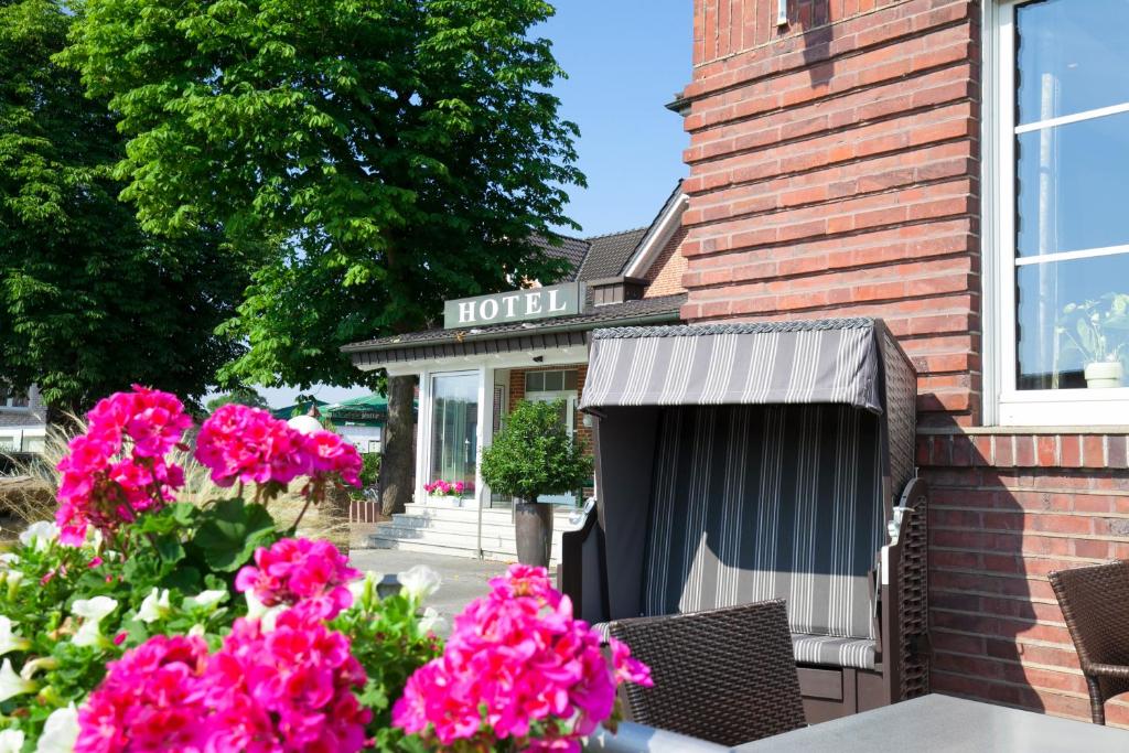a hotel with pink flowers in front of a building at Landgasthof-Hotel Zum Steverstrand in Lüdinghausen
