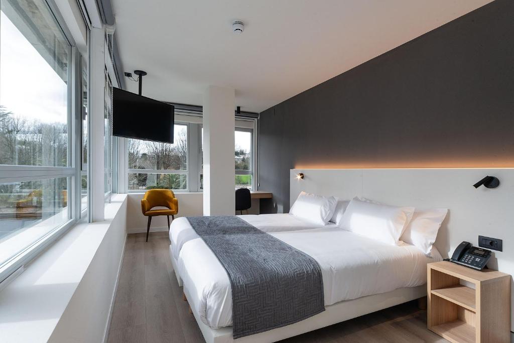 um quarto com uma cama grande e uma janela grande em Hotel Distrito Oeste em San Sebastián