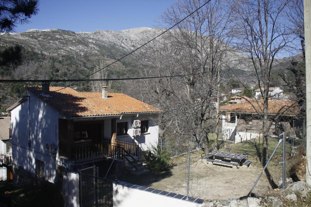 Casa Rural Las Pegueras في أفيلا: منزل ذو سقف أزرق مع جبال في الخلفية