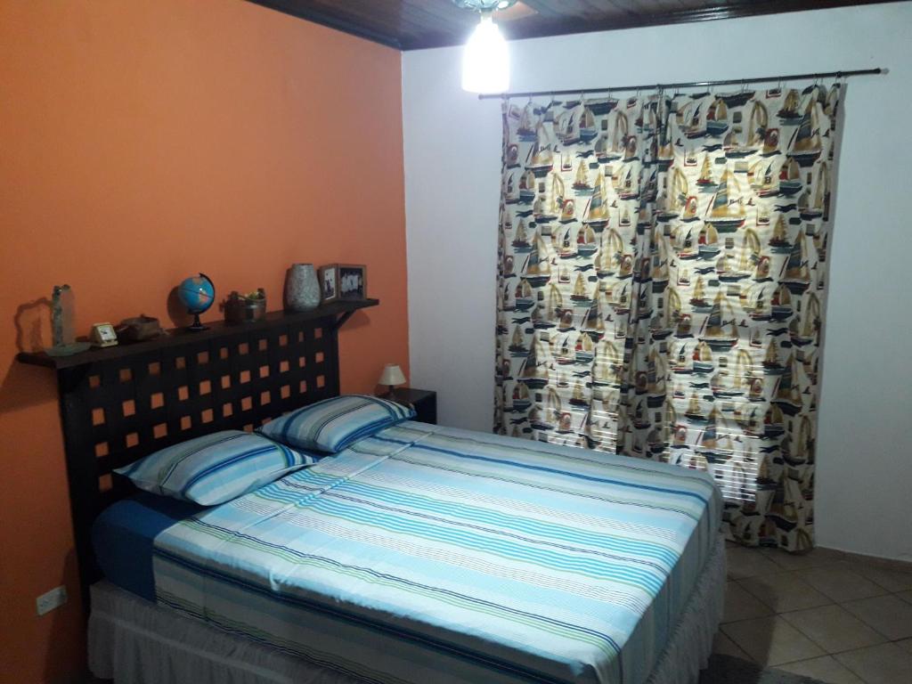 1 dormitorio con cama y ventana con cortina en Casa Vista Ilhabela com piscina e wi-fi, en Ilhabela