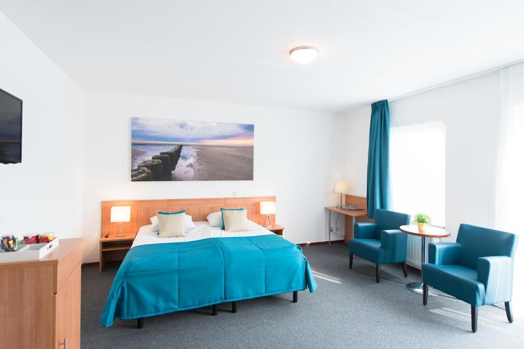 een slaapkamer met een blauw bed en 2 blauwe stoelen bij Hotel Nes in Nes