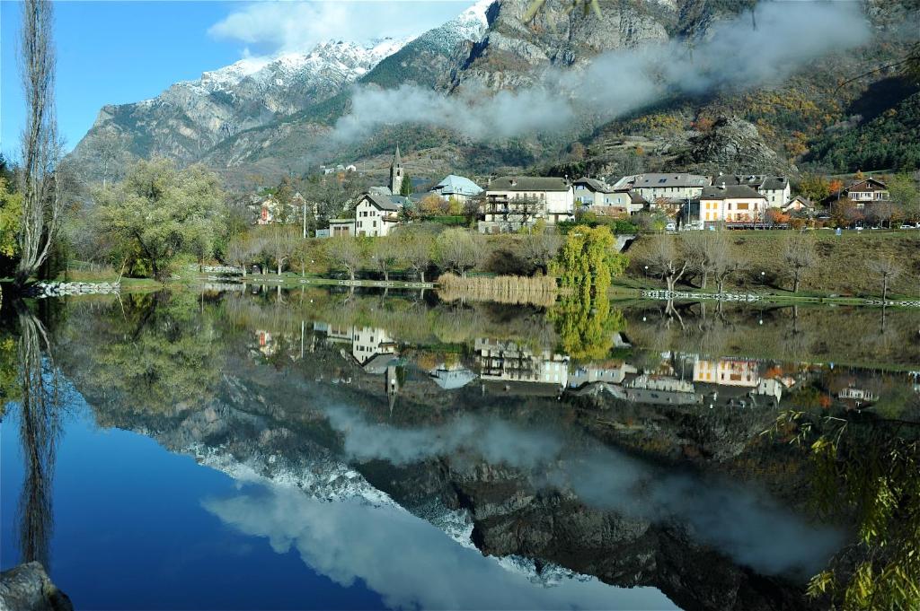 a reflection of a town on a lake with a mountain at Résidence les Bords du Lac in Le Lauzet-Ubaye