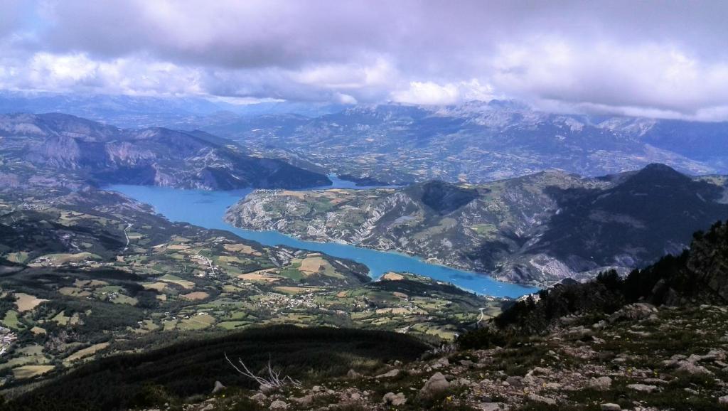 a view of a mountain valley with a blue lake at Résidence les Bords du Lac in Le Lauzet-Ubaye