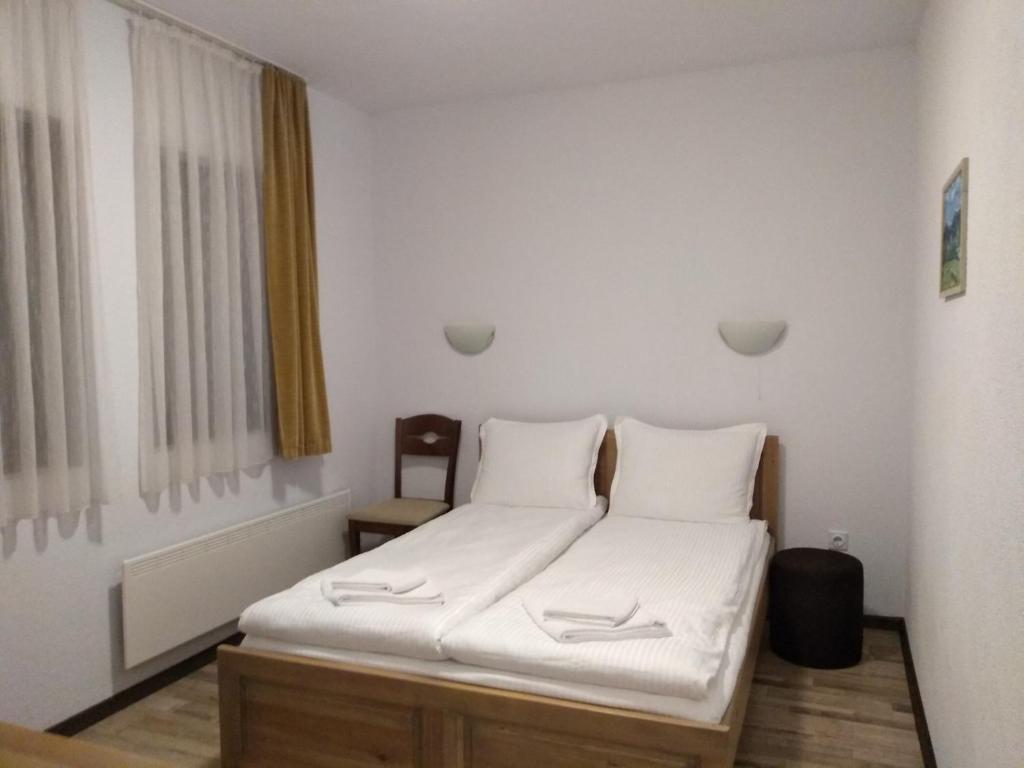 a bedroom with a bed with white sheets and a window at Guesthouse White Margarit in Melnik
