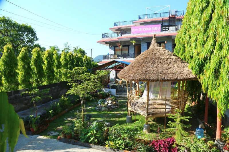 a building with a straw hut in a garden at Hotel Cherry Garden in Pokhara