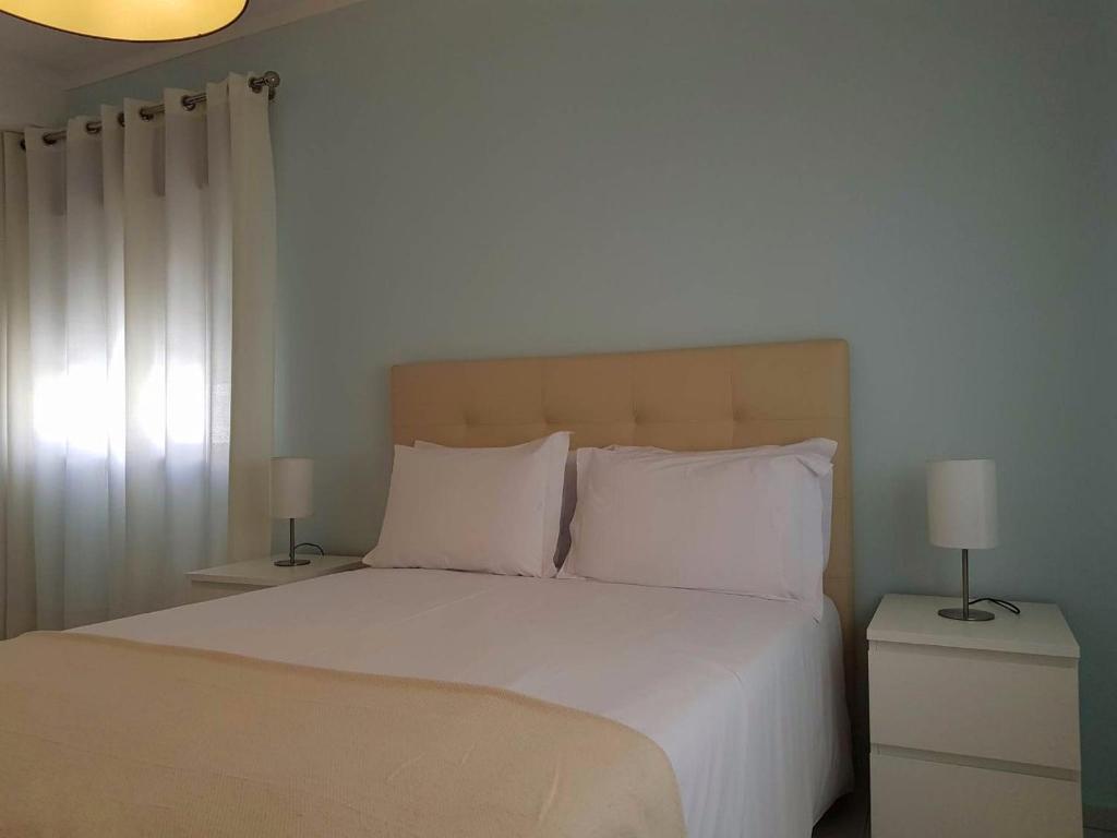 a bedroom with a bed with white sheets and pillows at Casa da Praia in Armação de Pêra