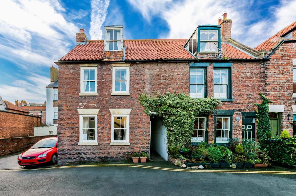 a brick house with a red car parked in front at Griffin Cottage in Whitby