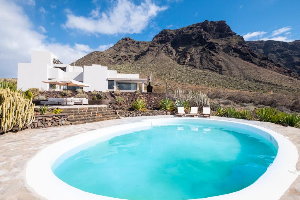 une villa avec une piscine en face d'une montagne dans l'établissement Villa Luxury Punta de Teno - Canary Good Vibes, à Buenavista del Norte