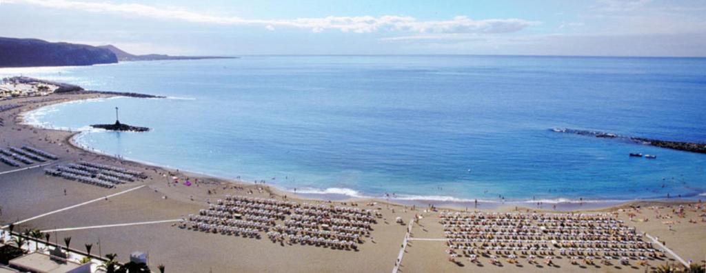 een strand met veel stoelen en de oceaan bij Las Vistas view in Los Cristianos