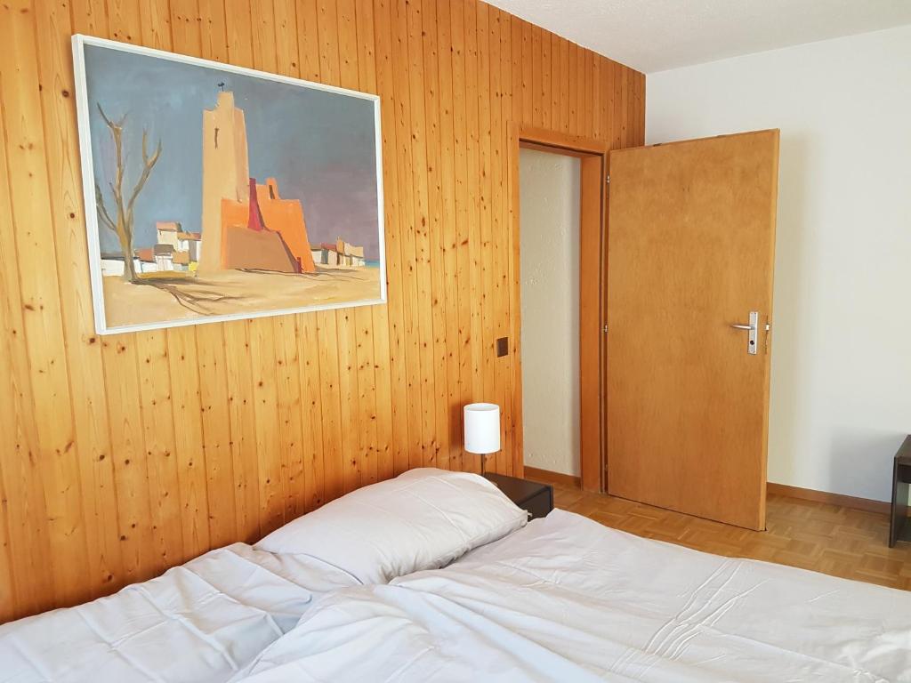 Auberge de la Couronne في ساينليجيي: غرفة نوم بسرير وجدار خشبي