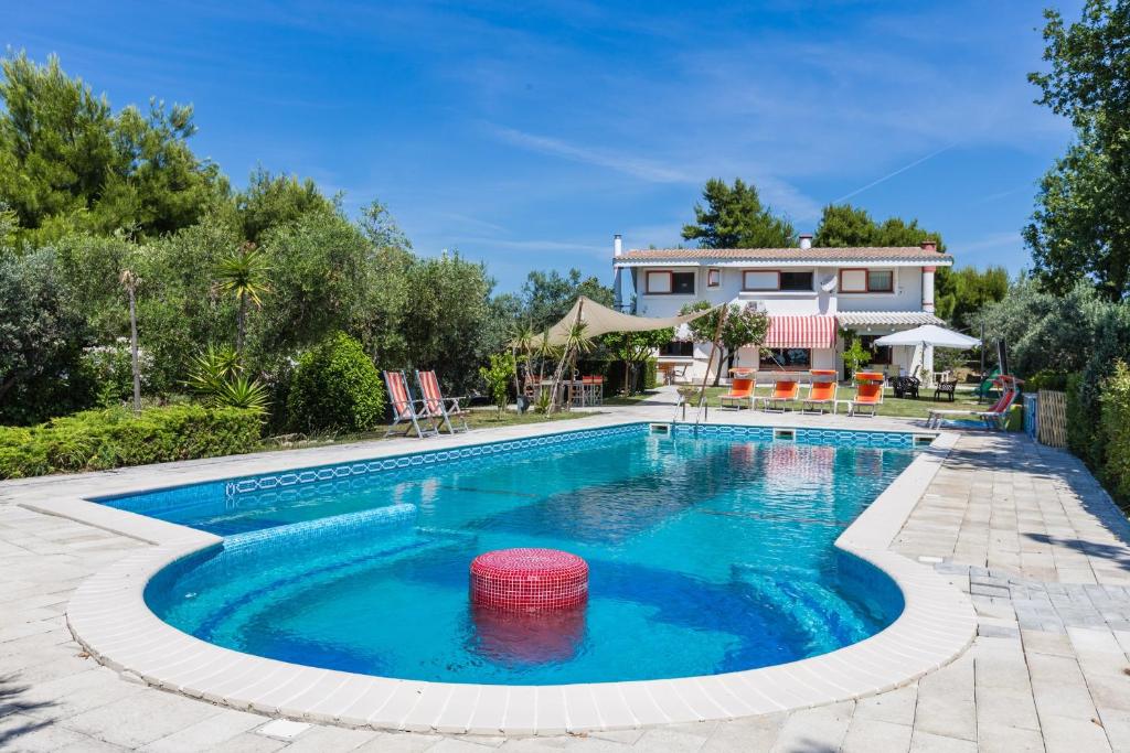 une piscine avec une maison en arrière-plan dans l'établissement Villa Claudia, à Alba Adriatica