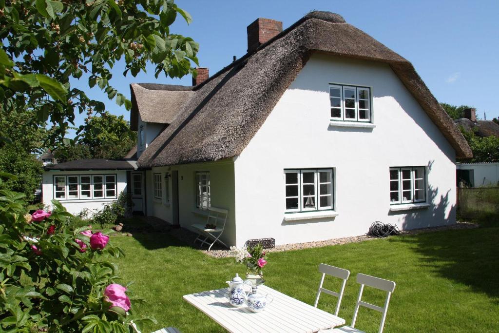 a white cottage with a thatched roof at Friesenhaus Amrum Friesenhaushälfte *Klönschnack* in Süddorf
