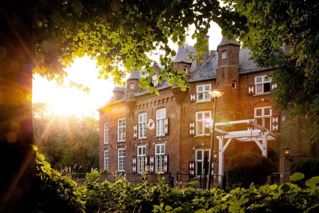 a large brick building with the sun in the background at B&B Kasteel Maurick in Vught