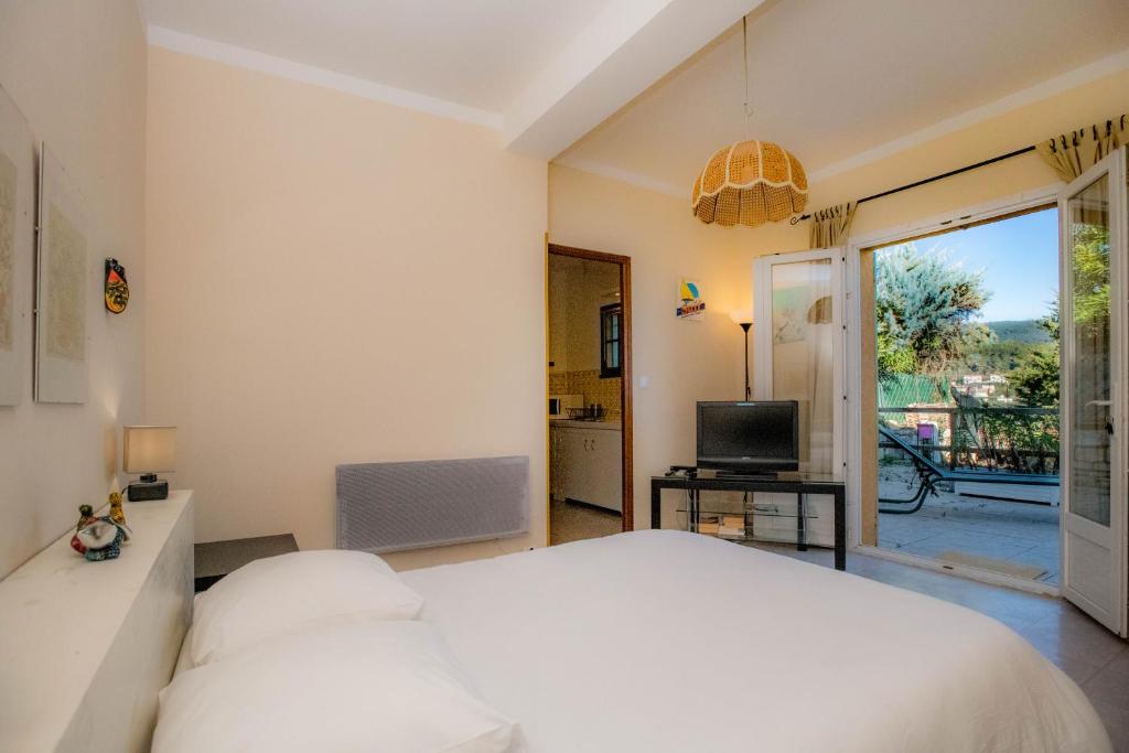 1 dormitorio con cama blanca y balcón en B&B Chez Max, en Figanières