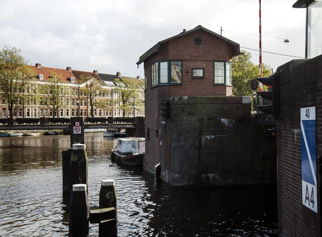 a building sitting on the side of a river at SWEETS - Kattenslootbrug in Amsterdam