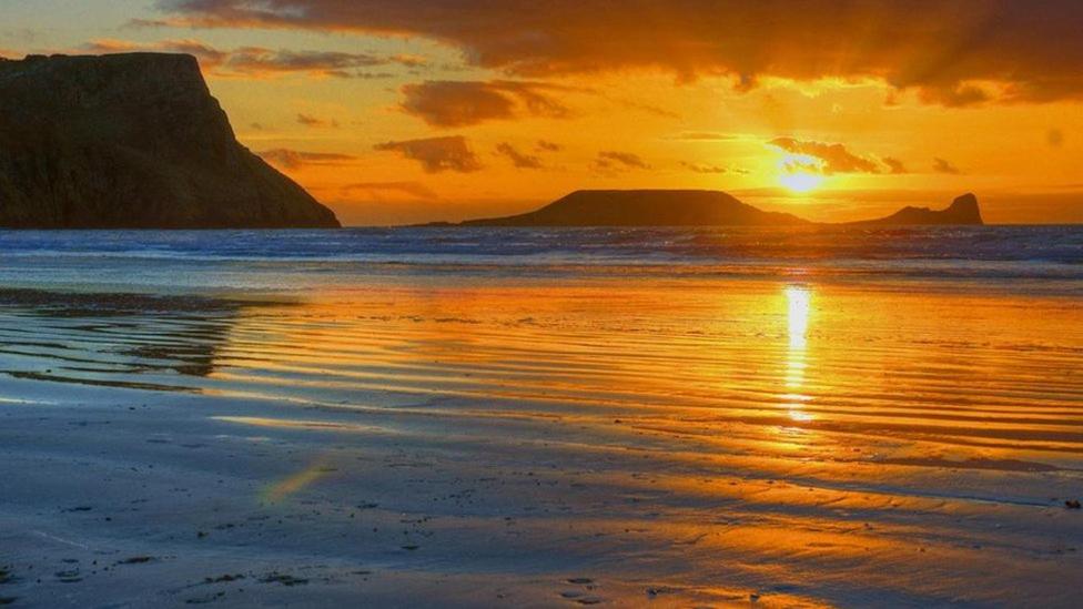 a sunset on a beach with the ocean at King's Head Inn in Llangennith