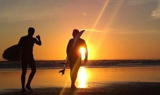 two men walking on the beach at sunset at King's Head Inn in Llangennith