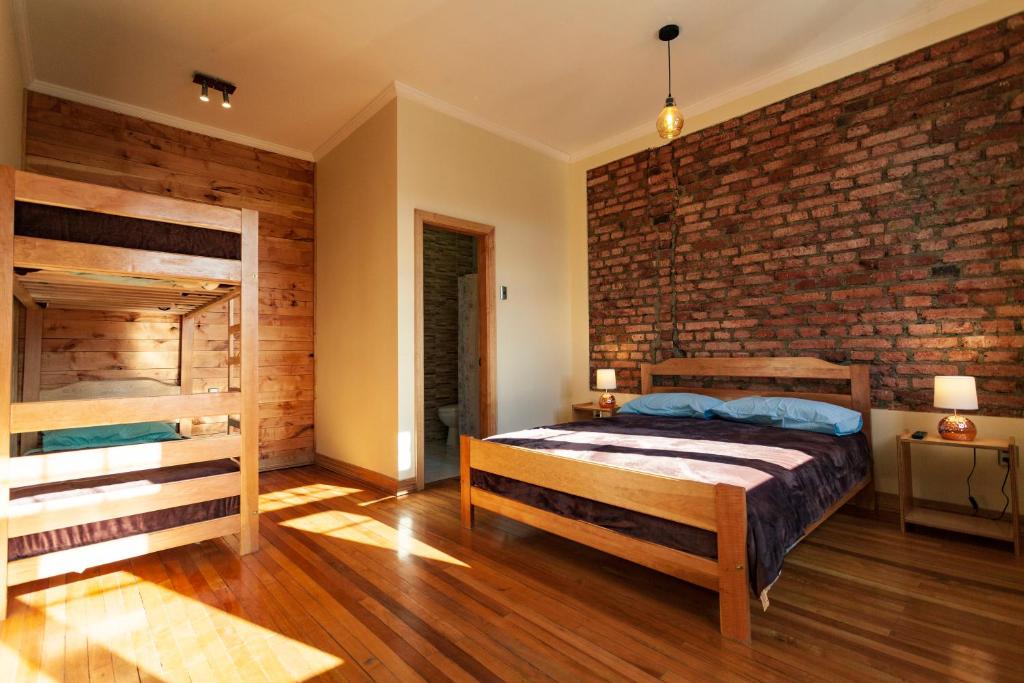 1 dormitorio con cama y pared de ladrillo en Hostal Boutique Patagonia Mística en Punta Arenas