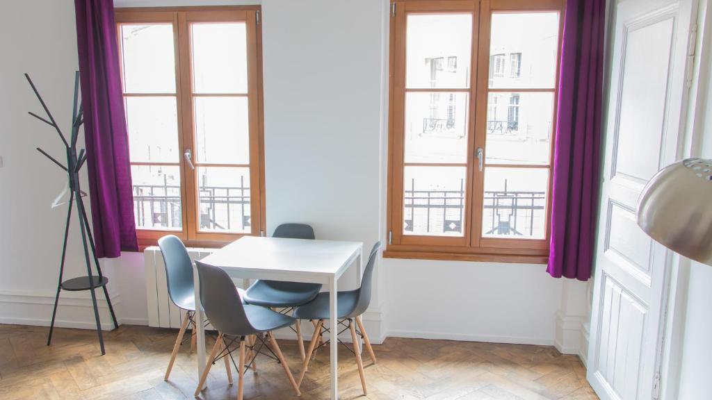a table and chairs in a room with windows at Les Appartements Rue des Veaux - Quartier Cathédrale in Strasbourg