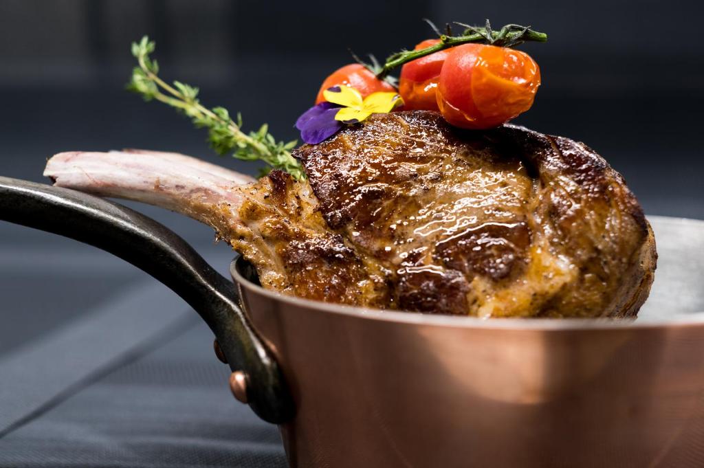a piece of meat in a pot with vegetables on it at Hôtel du Cygne in Bevaix