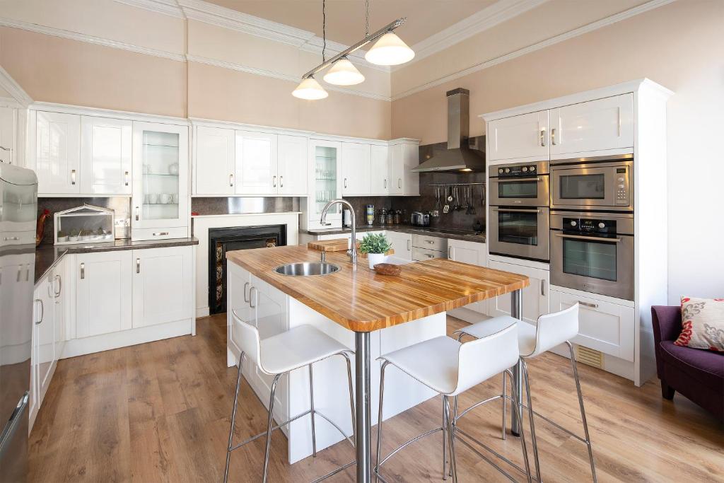 une cuisine avec des placards blancs et un comptoir en bois dans l'établissement Stunning Spacious Central Apartment near Parade Gardens, à Bath