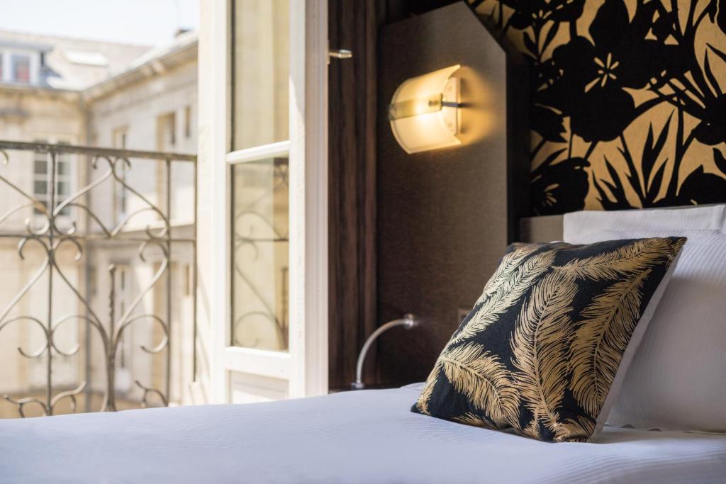 a pillow sitting on a bed next to a window at Hotel Voltaire Opera Nantes Centre in Nantes