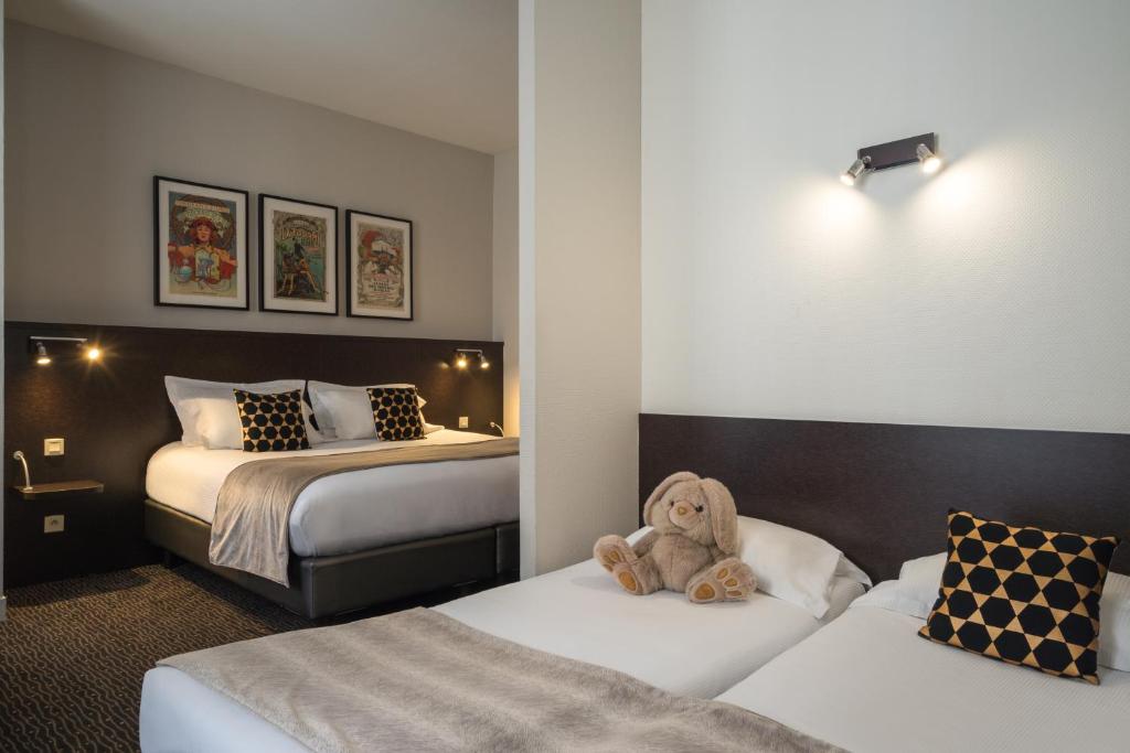 a teddy bear sitting on two beds in a hotel room at Hotel Voltaire Opera Nantes Centre in Nantes
