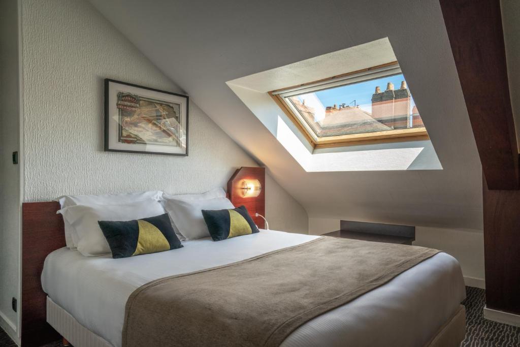 a bedroom with a large bed with a skylight at Hotel Voltaire Opera Nantes Centre in Nantes