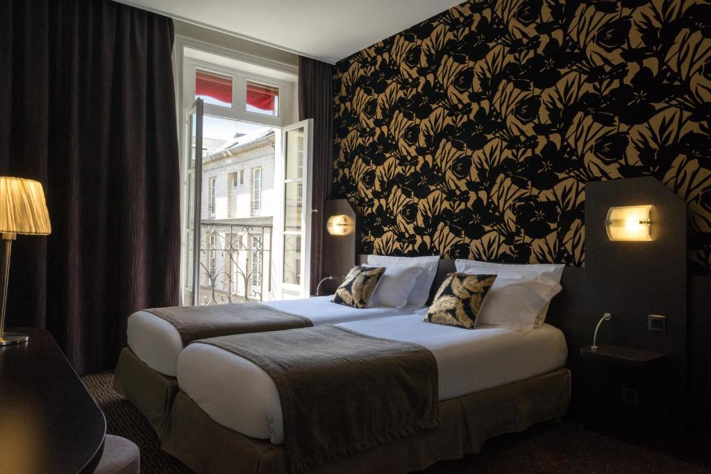 a hotel room with two beds and a window at Hotel Voltaire Opera Nantes Centre in Nantes