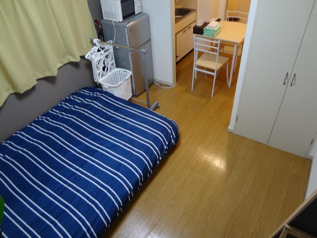 een kamer met een bed, een bureau en een tafel bij Guest House ZEN HAKATA Ohori Park in Fukuoka
