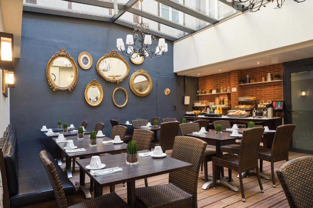 a restaurant with tables and chairs and mirrors on the wall at Hotel Voltaire Opera Nantes Centre in Nantes