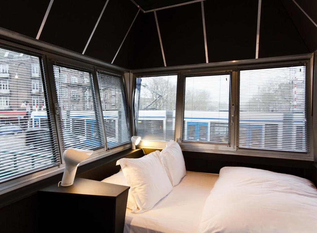 ein Schlafzimmer mit weißen Kissen und ein Bett mit Fenstern in der Unterkunft SWEETS - Wiegbrug in Amsterdam