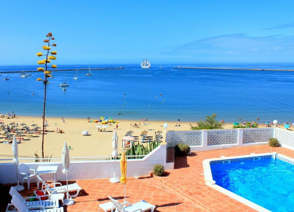 a resort with a swimming pool and a beach at Vila Monte Luz in Ferragudo